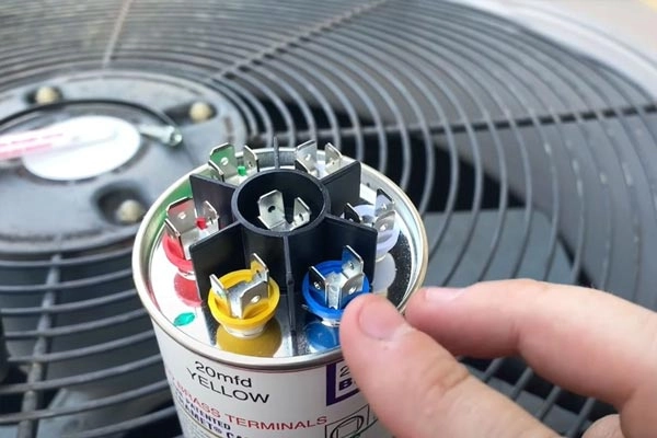 Dye Plumbing & Heating technician testing a run capacitor during spring AC startup diagnostic